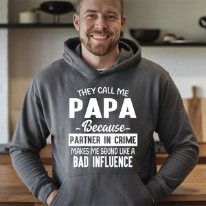 A man wearing a grey hoodie with text printed on it, smiling at the camera.