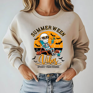 A woman wearing a beige sweater with a graphic design featuring a skeleton wearing sunglasses and holding a drink, along with the text "Summer Ween Vibes Spooky Year Round".