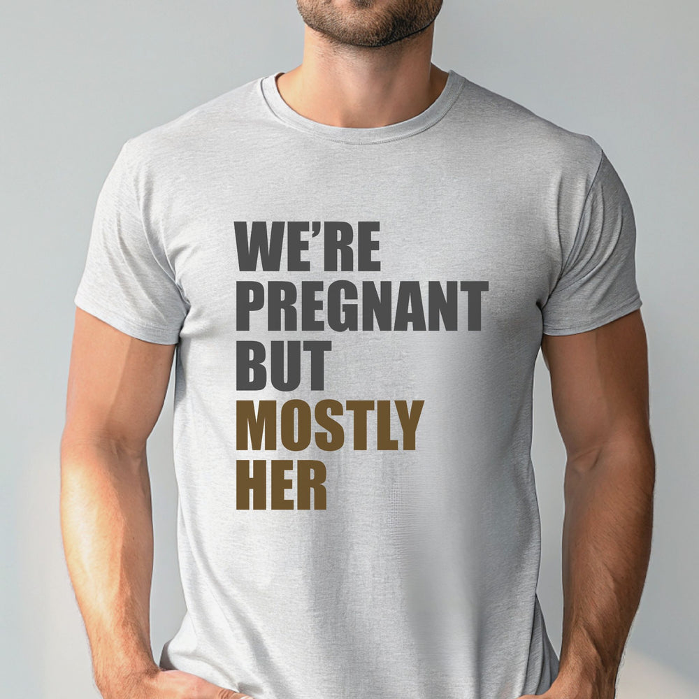 A man wearing a white t-shirt with the text "WE'RE PREGNANT BUT MOSTLY HER" printed on it.