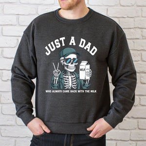 A man wearing a gray sweatshirt with a graphic design of a skeleton holding a carton of milk and the text "Just a Dad" printed on it.
