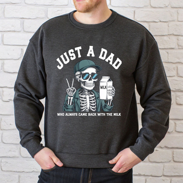 A man wearing a gray sweatshirt with a graphic design of a skeleton holding a carton of milk and the text "Just a Dad" printed on it.