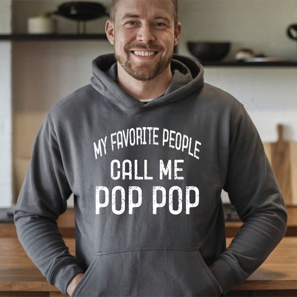 A man wearing a gray hoodie with the text "MY FAVORITE PEOPLE CALL ME POP POP" printed on it, smiling at the camera.