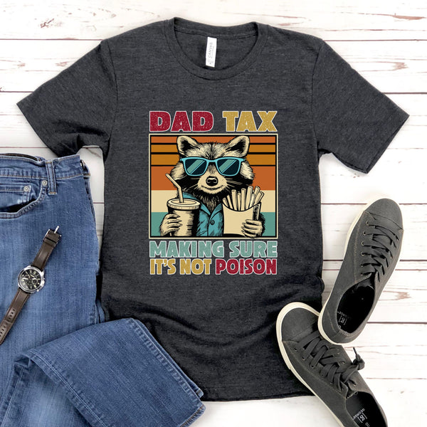 a gray t-shirt with a graphic design of a raccoon wearing sunglasses and holding a drink, accompanied by the text "DAD TAX MAKING SURE IT'S NOT POISON".