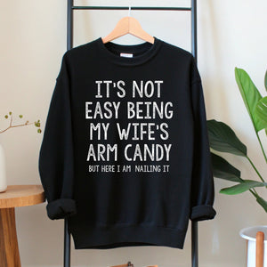 A black sweatshirt with white text hanging on a wooden hanger.