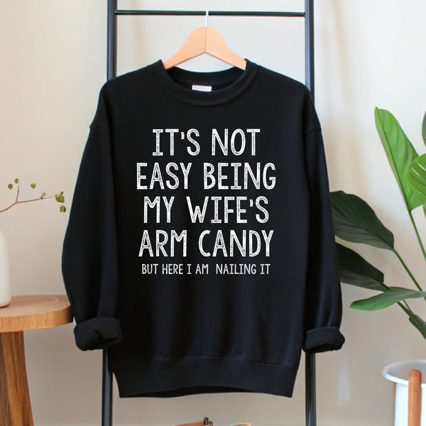 A black sweatshirt with white text hanging on a wooden hanger.