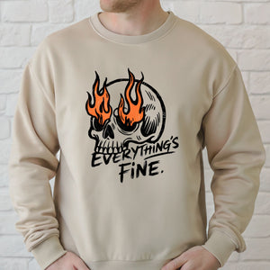 A man wearing a beige sweater with a graphic design featuring a skull with flames and the text "Everything's Fine" printed on it.