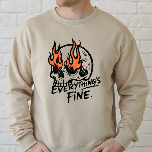 A man wearing a beige sweater with a graphic design featuring a skull with flames and the text "Everything's Fine" printed on it.