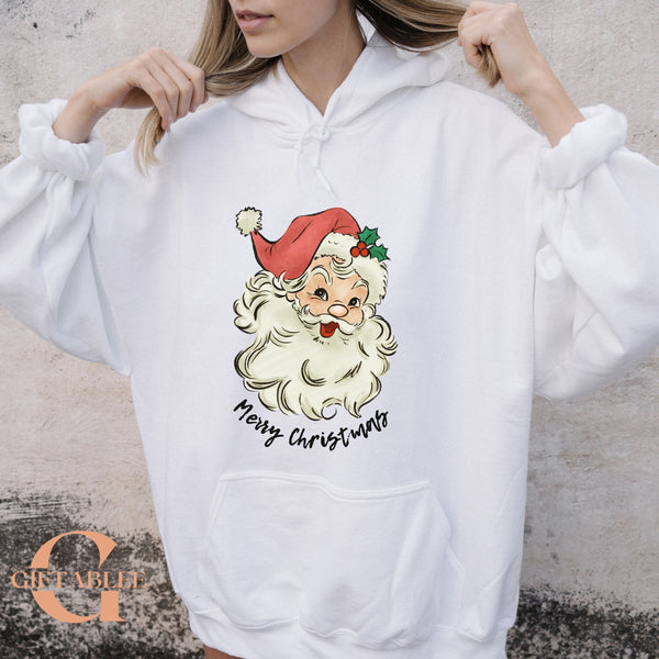 A woman wearing a white hoodie with a graphic of Santa Claus and the text "Merry Christmas" printed on it.