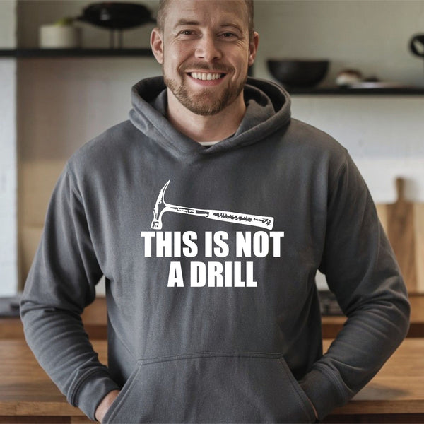 A man wearing a grey hoodie with the text "THIS IS NOT A DRILL" printed on it, smiling at the camera.