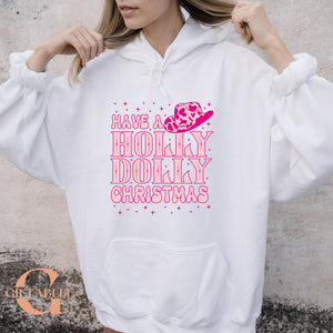 A woman wearing a white hoodie with a pink and white design that says "Have a Holly Dolly Christmas".