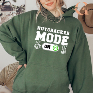 A person wearing a green hoodie with the text "NUTCRACKER MODE ON" printed on it.