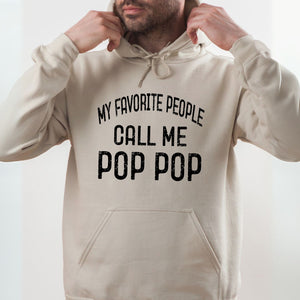 A man wearing a beige hoodie with the text "MY FAVORITE PEOPLE CALL ME POP POP" printed on it.