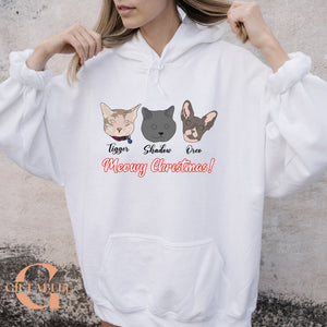 A person wearing a white hoodie with a graphic design featuring three cat faces and the text "Meowy Christmas!"