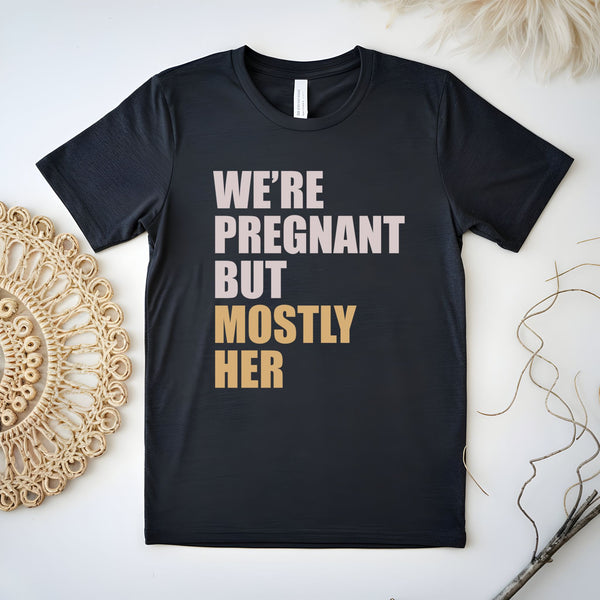 A black t-shirt with text printed on it, placed on a white surface next to a woven object.