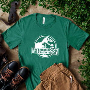 a green t-shirt with a white graphic and text, a pair of black shoes, and some greenery, all laid out on a surface.