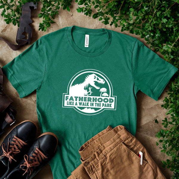 a green t-shirt with a white graphic and text, a pair of black shoes, and some greenery, all laid out on a surface.