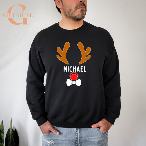 A man wearing a black sweatshirt with a graphic design featuring a pair of orange antlers and the name "MICHAEL" printed on it.