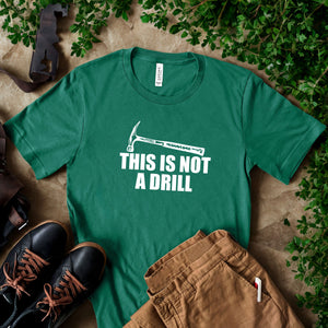 a green t-shirt with a humorous text printed on it, along with a pair of brown pants and black shoes, all laid out on a surface with some greenery.