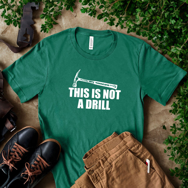 a green t-shirt with a humorous text printed on it, along with a pair of brown pants and black shoes, all laid out on a surface with some greenery.